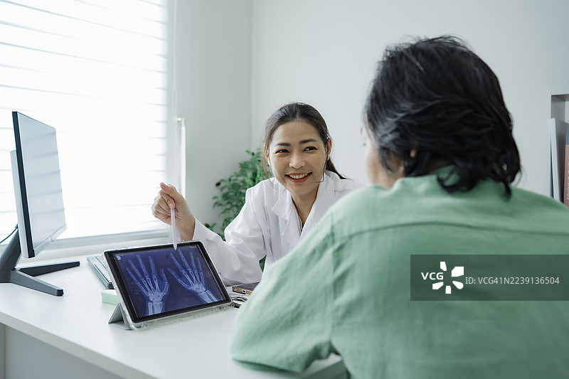 专业护士在数字平板电脑上展示X光片进行诊断，代表了医疗技术的创新。图片素材