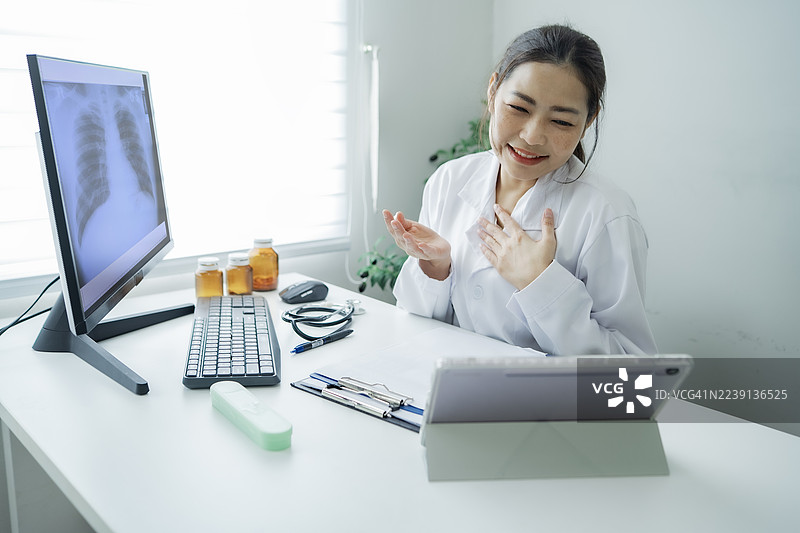 一位女医生在现代诊所办公室通过数字平板电脑进行视频通话咨询病人。图片素材