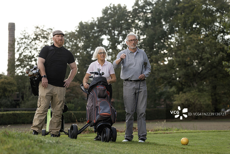 欧洲一对退休夫妇和他们的球童在打高尔夫球图片素材