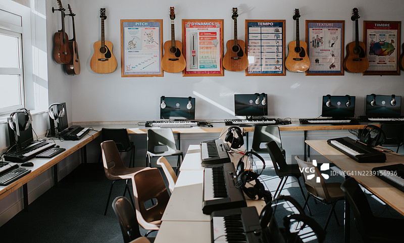 午后阳光下，现代音乐教室配有乐器和电脑，供创意学习。图片素材