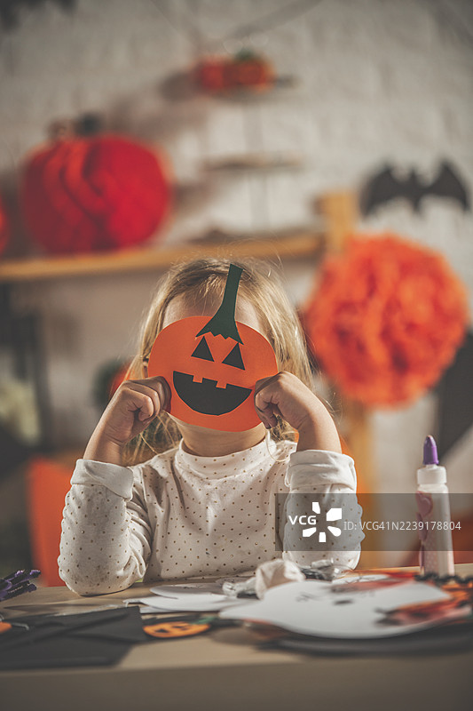 儿童制作万圣节南瓜灯面具，用于有趣的家庭摄影。图片素材