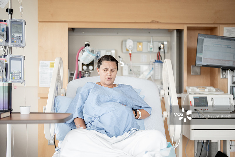 孕妇在病床上分娩，背景有医疗设备图片素材