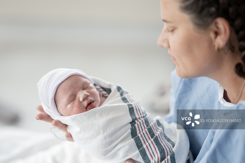 新生儿出生后在医院被母亲抱着，裹在毯子里图片素材