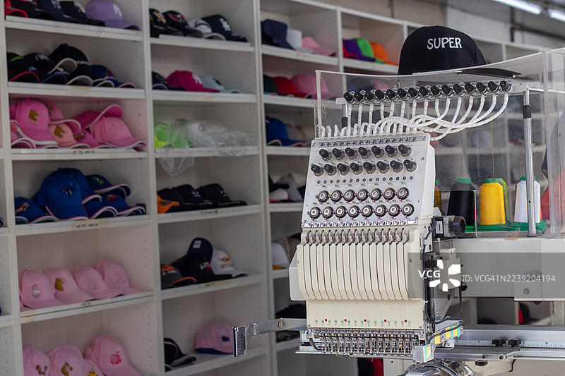 帽子店里的刺绣机，展示架上摆满了帽子和便帽图片素材