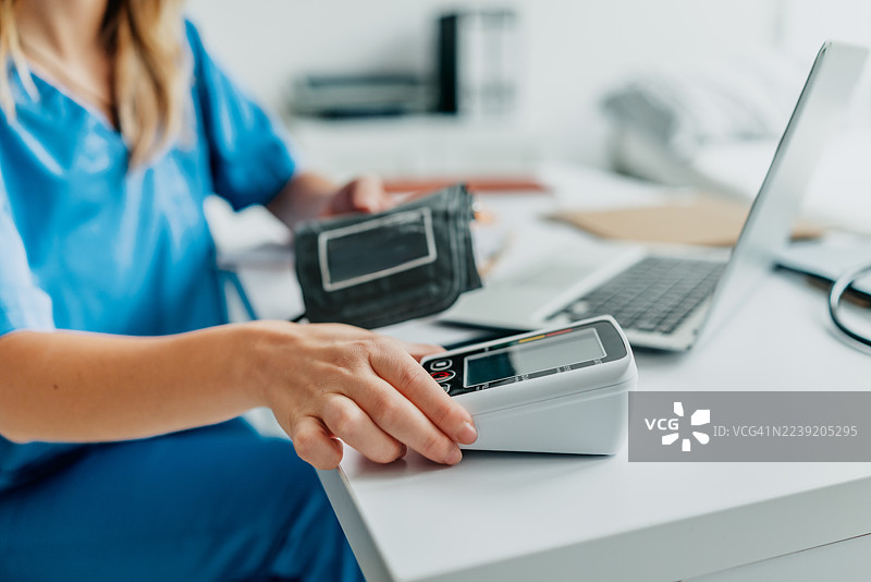 一位女性医护人员在诊所进行体检并使用血压计图片素材
