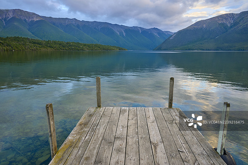 日出时分，木制人行桥通向湖泊，背景是群山，夏季，新西兰南岛塔斯曼地区圣阿尔诺罗托伊蒂湖，大洋洲图片素材