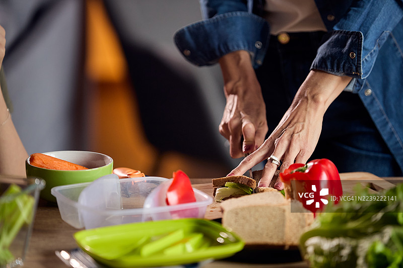 一个人在厨房的台面上用新鲜蔬菜和面包准备三明治图片素材