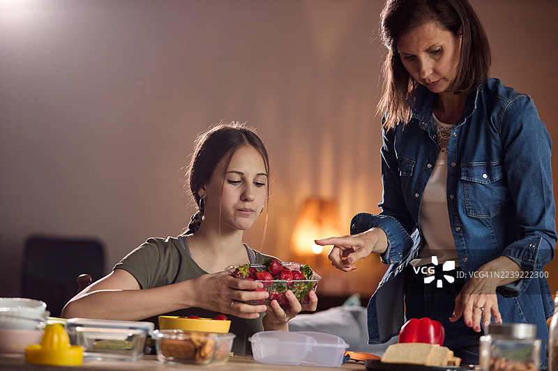 母亲和女儿在温馨的厨房里准备新鲜草莓，共享宁静而充满关爱的烹饪时刻图片素材