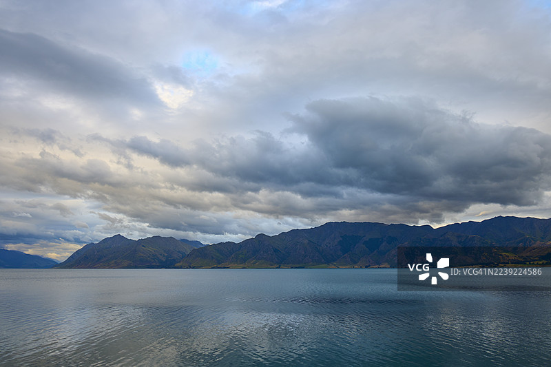 新西兰南岛奥塔哥哈威亚哈威亚湖，湖面平静，远眺多云的山脉图片素材