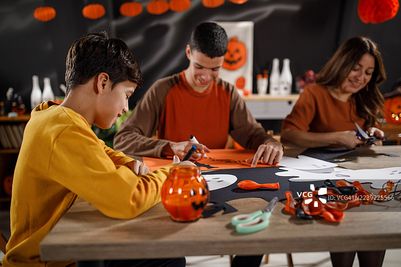 妈妈和两个儿子制作万圣节纸装饰品图片素材