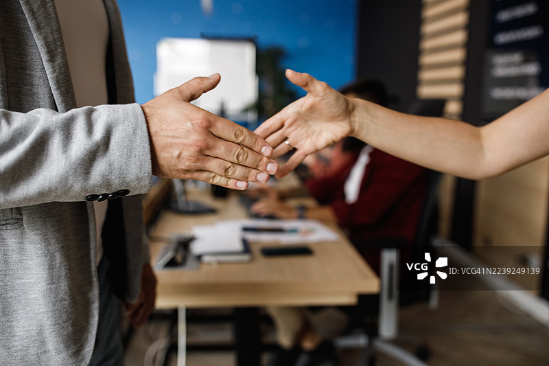 两人在现代办公室握手，象征着合作、协议和专业的团队合作图片素材