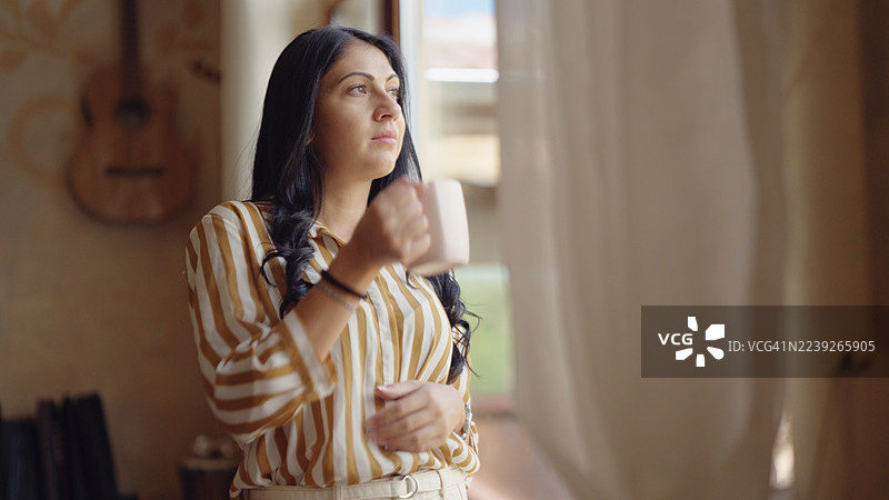 早晨咖啡。年轻女子在喝第一杯咖啡时眺望大自然，若有所思。图片素材