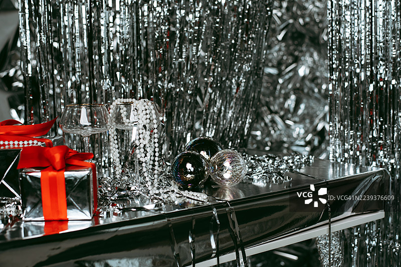 新年银色静物。银色背景上的礼物和玻璃杯。新年。圣诞节。图片素材