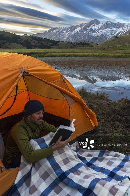 男人在湖边的帐篷门口看书图片素材