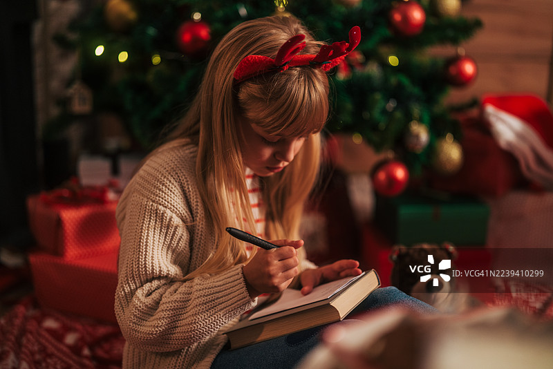 小女孩正在写给圣诞老人的圣诞愿望清单信图片素材