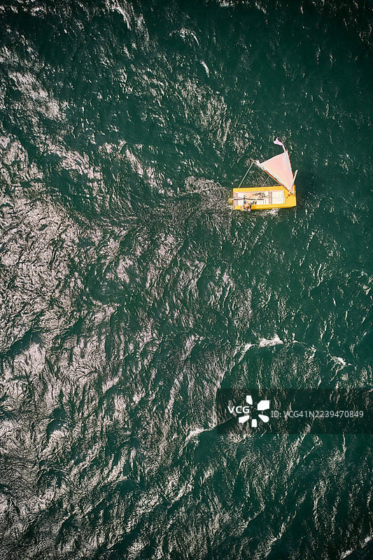 一艘黄色帆船，白帆，在塔阿尔湖碧绿的海面上，俯瞰视角图片素材