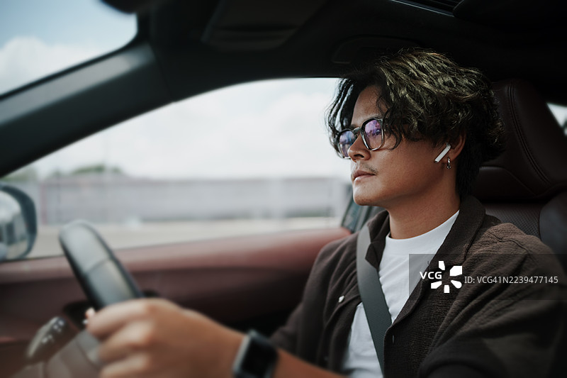 亚洲男子在公路旅行中开车。图片素材