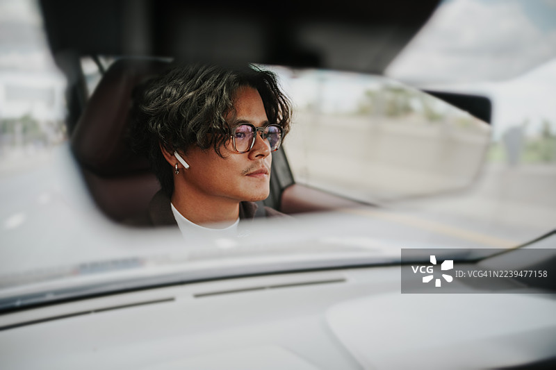 年轻亚洲男子开车的倒影。图片素材