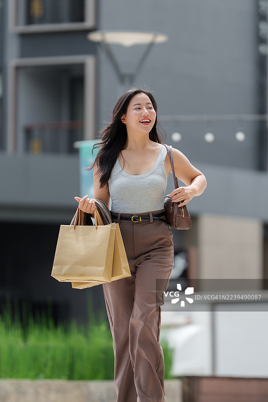 年轻的亚洲女性提着购物袋，面带微笑图片素材