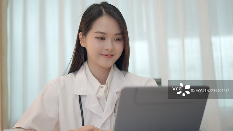 女医生坐在诊室里，远程与患者沟通，查阅病历，评估病情进展，并就生活方式改善提供建议。虚拟健康检查使患者足不出户即可获得持续的护理。。图片素材