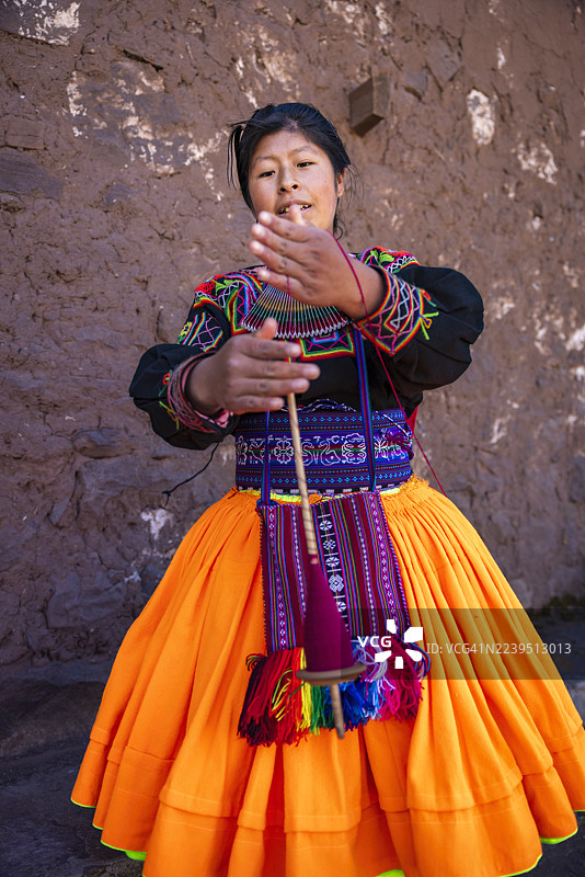 秘鲁的的喀喀湖塔基莱岛上，一位年轻女子正在手工纺羊毛。图片素材