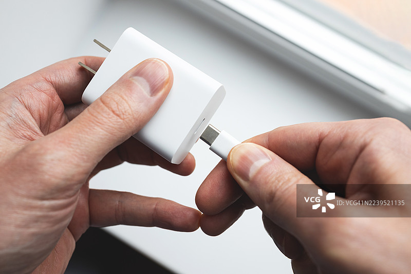 一个人将充电器连接到电源适配器图片素材