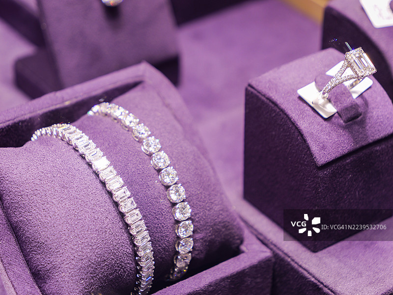 紫色天鹅绒精品展示台上的钻石手链和戒指套装。图片素材
