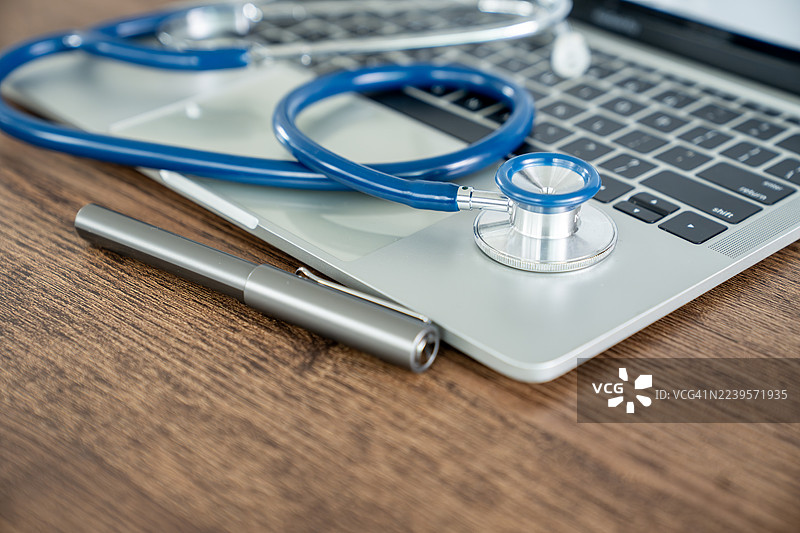 医生办公室的桌子上放着听诊器和笔记本电脑图片素材