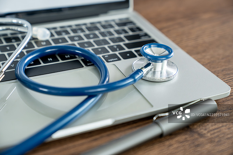 医生办公室的桌子上放着听诊器和笔记本电脑图片素材