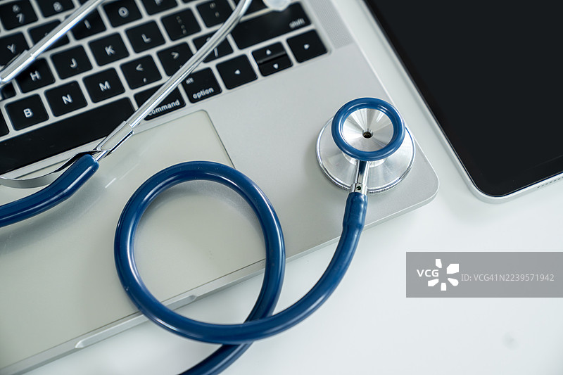 医生办公室的桌子上放着听诊器和笔记本电脑图片素材