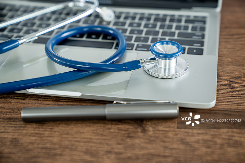 医生办公室的桌子上放着医用听诊器和笔记本电脑图片素材