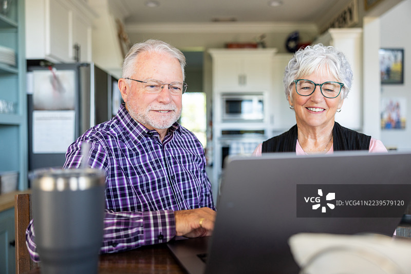 老年夫妇准备周末度假，通过电脑进行研究图片素材