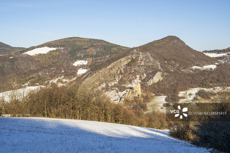 斯洛伐克霍尔纳波鲁巴瓦佩奇的切尔沃诺卡门斯凯悬崖(Cervenokamenske Bradlo),冬季时节,山上有灌木、树木和草地的巨大岩石图片素材