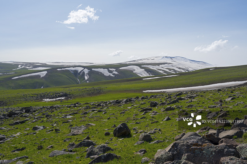 散落着石块和雪地的开阔绿色草地一直延伸到地平线,通往阿拉加兹山的路上的风景,阿拉加兹山,阿拉加茨,阿拉格亚兹,休眠的成层火山,4090米,阿拉加措特恩省,希拉克省,亚美尼亚图片素材