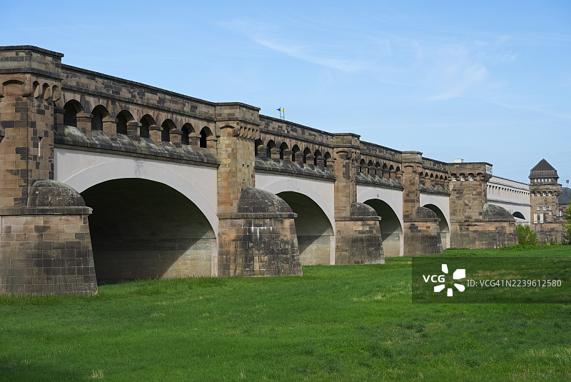 历史悠久的拱形石桥,旁边是绿色的草地,蓝天白云下,水道交汇处,横跨米特兰海峡运河与威悉河的古老桥梁,水槽桥,位于德国北莱茵-威斯特法伦州明登市。图片素材