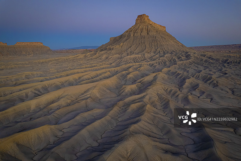 日落时分，戏剧性的沙漠景观，雄伟的孤山在暮光的天空中，展示了自然的侵蚀模式，美国，美国，韦恩县图片素材