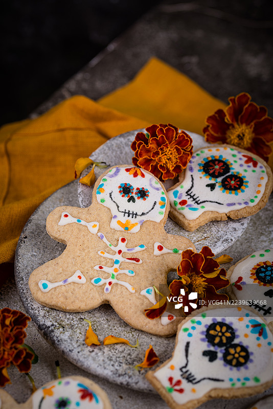 俯视角度拍摄的装饰好的姜饼，为亡灵节庆典而制，上面有骷髅和骨架图案，并点缀着鲜艳的金盏花。图片素材