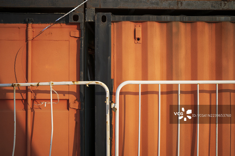 简约工业风格构图，包含橙色集装箱和白色栅栏。图片素材