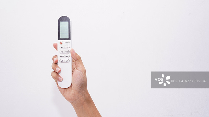 一只手握着空调遥控器。白色背景上孤立。图片素材