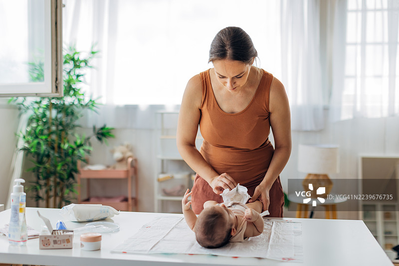 无忧无虑的母亲在家为平静的女婴更换尿布图片素材