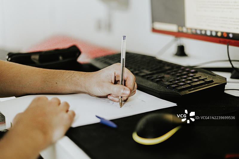 一名左撇子青少年的手在电脑前做数学练习的特写图片素材