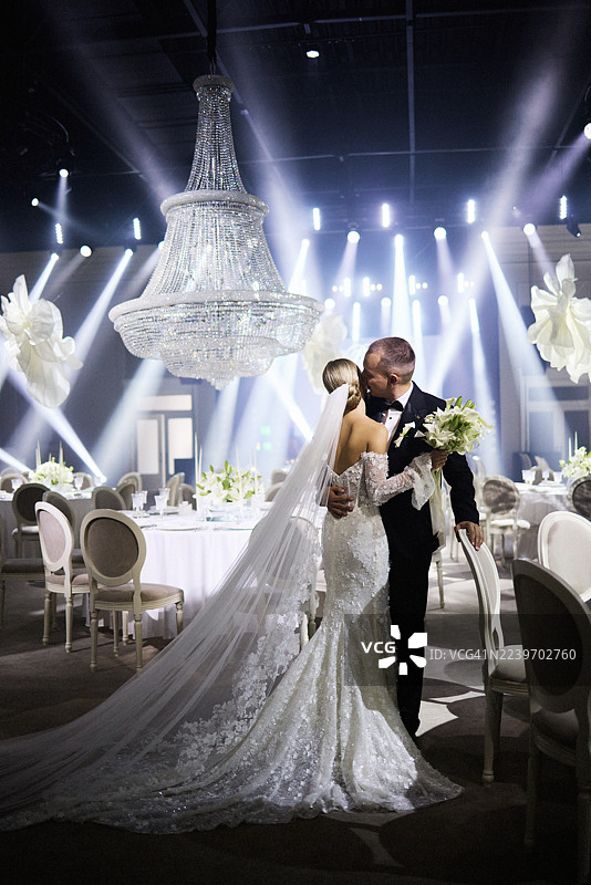 宏伟的场地内，灯光装饰下，一场优雅的婚礼庆典在夜晚举行。图片素材