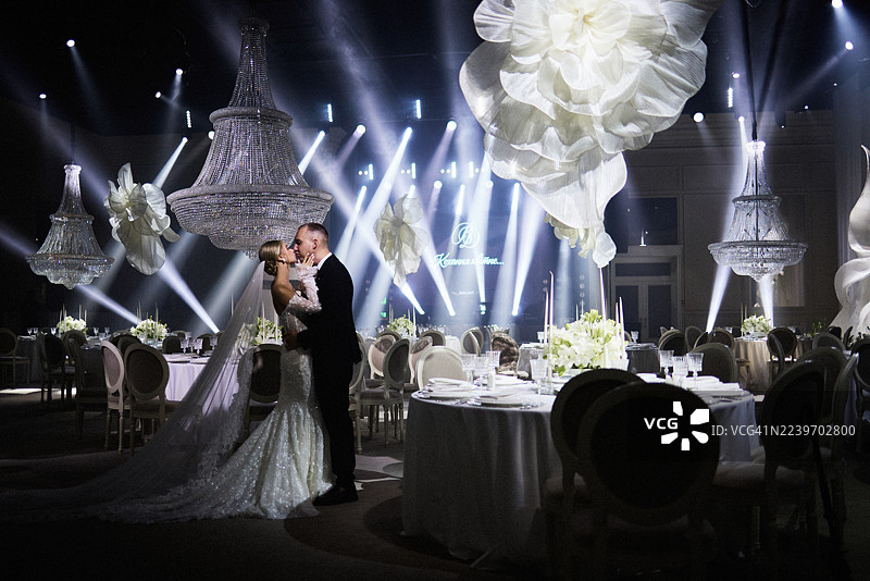 一对夫妇在装饰过的场地里，在他们的婚礼上分享了一个吻。图片素材