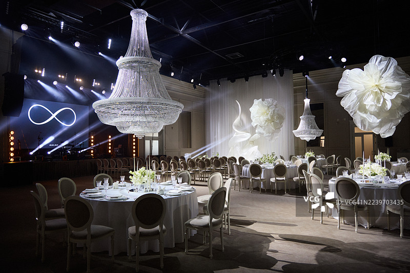 一个豪华的宴会厅装饰着巨大的飘逸鲜花，并由聚光灯照亮以庆祝。图片素材