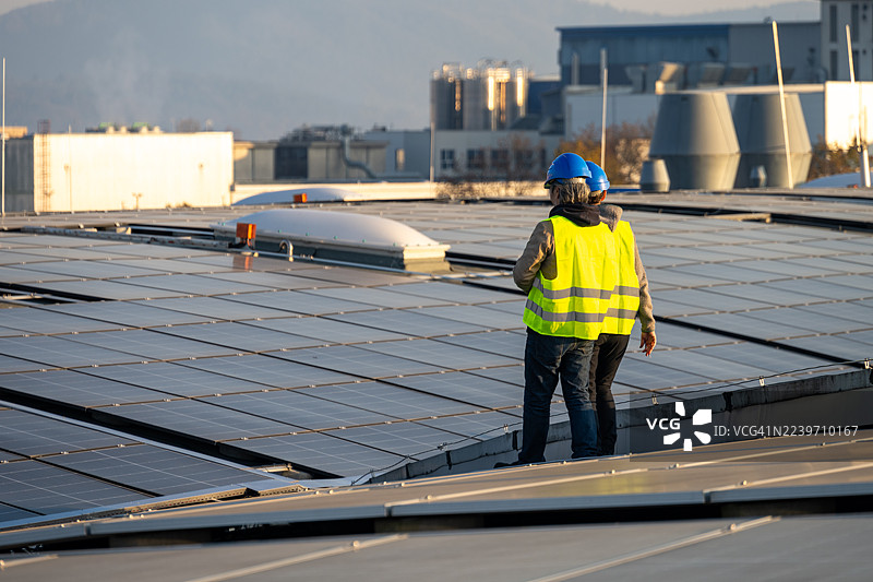 亚洲男性和白人女性检查工厂屋顶太阳能装置图片素材