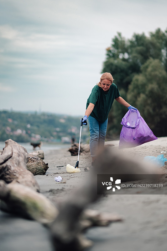 女志愿者在河岸海滩清理垃圾图片素材