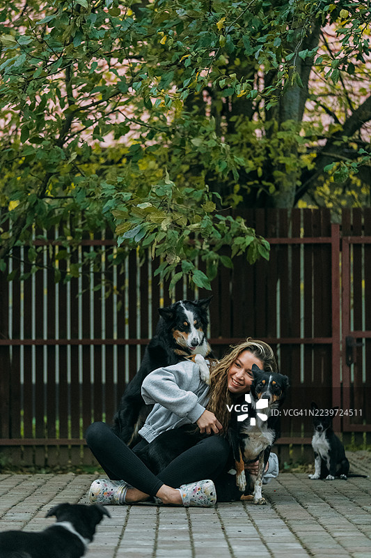 年轻女子与她的边境牧羊犬和幼犬享受时光图片素材