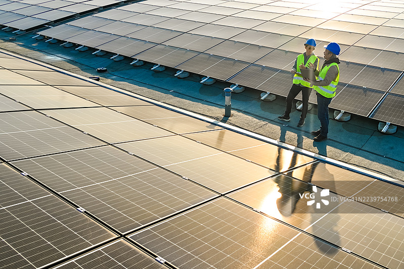 技术人员在工厂屋顶审查太阳能电池板效率图片素材