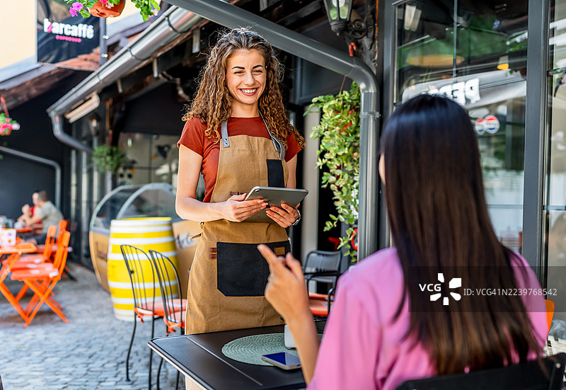 服务员在咖啡馆使用平板电脑接受顾客点单图片素材