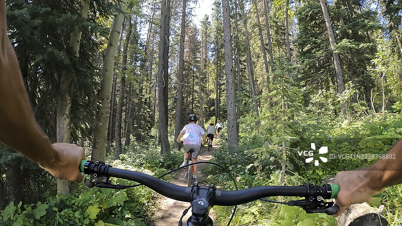 从自行车车把看到的视角，一家人在森林里骑行图片素材